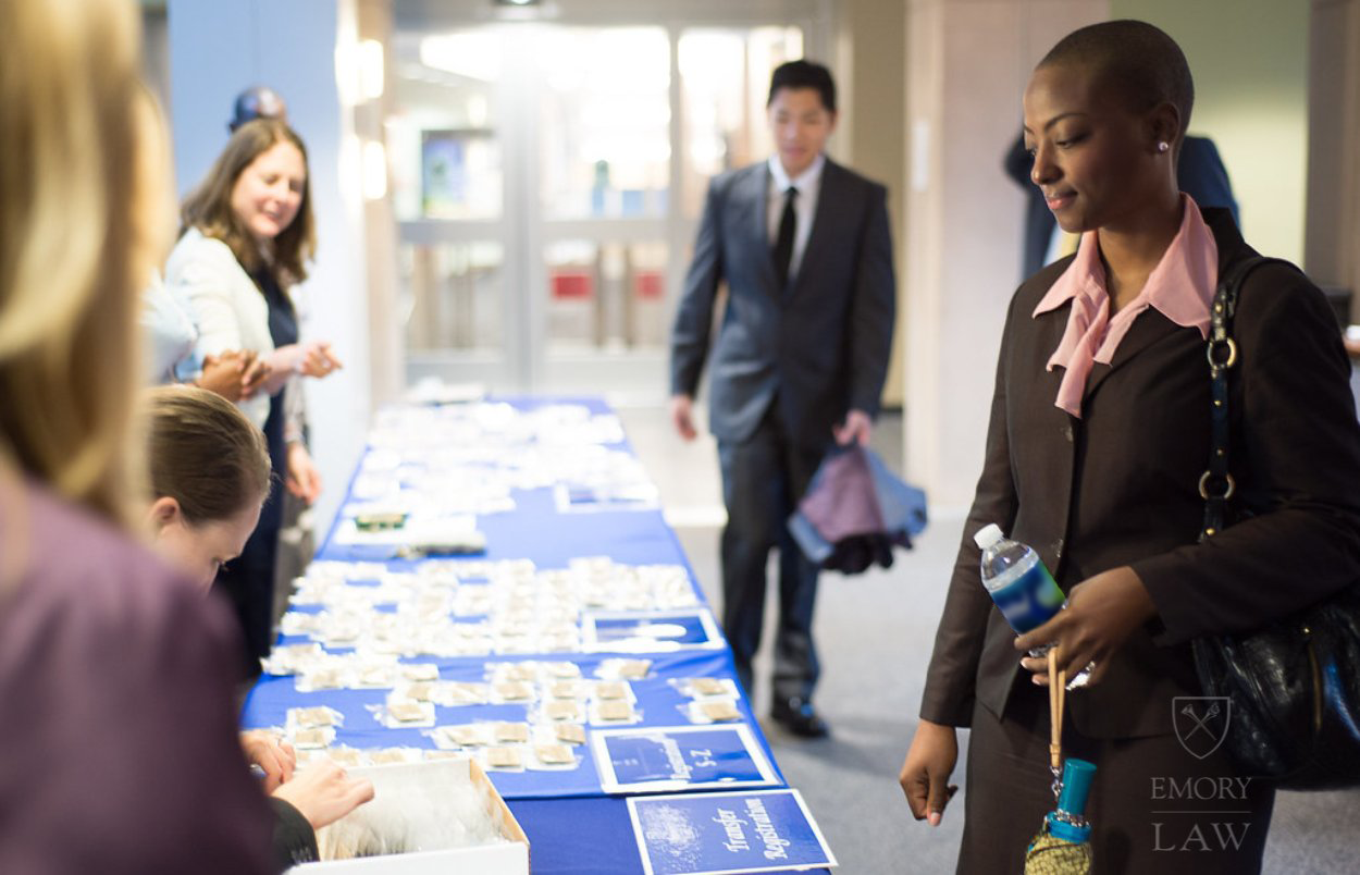 Law student in the foreground looks at promotional material at Emory Law table