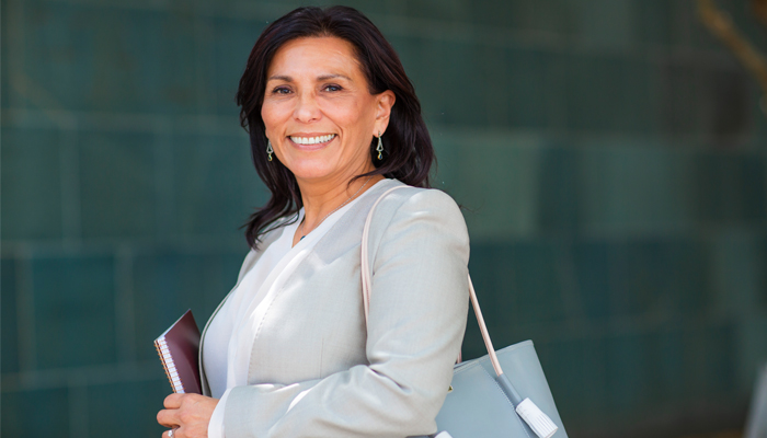 Woman in business suit and holding books smiling