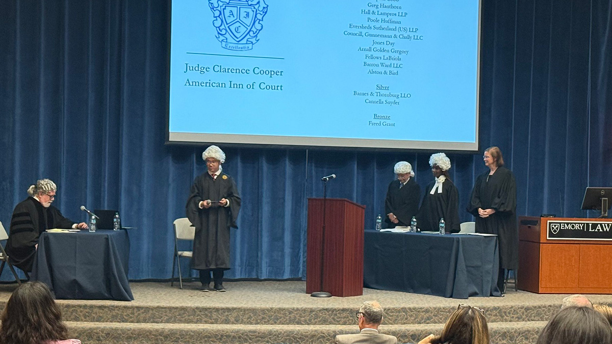 People on stage in judge robes and wigs performing a skit